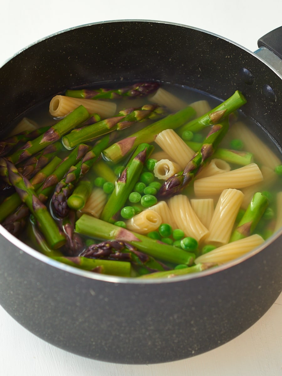 Pasta cooking with asparagus and peas