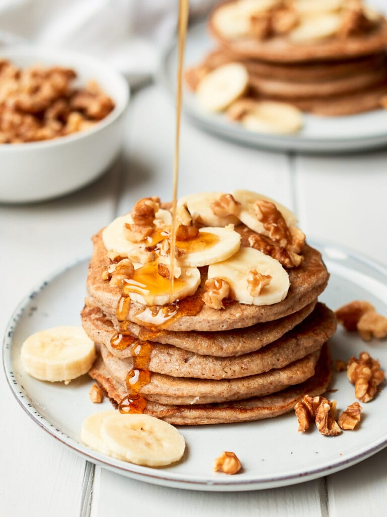 Stack of vegan banana pancakes with maple syrup drizzling