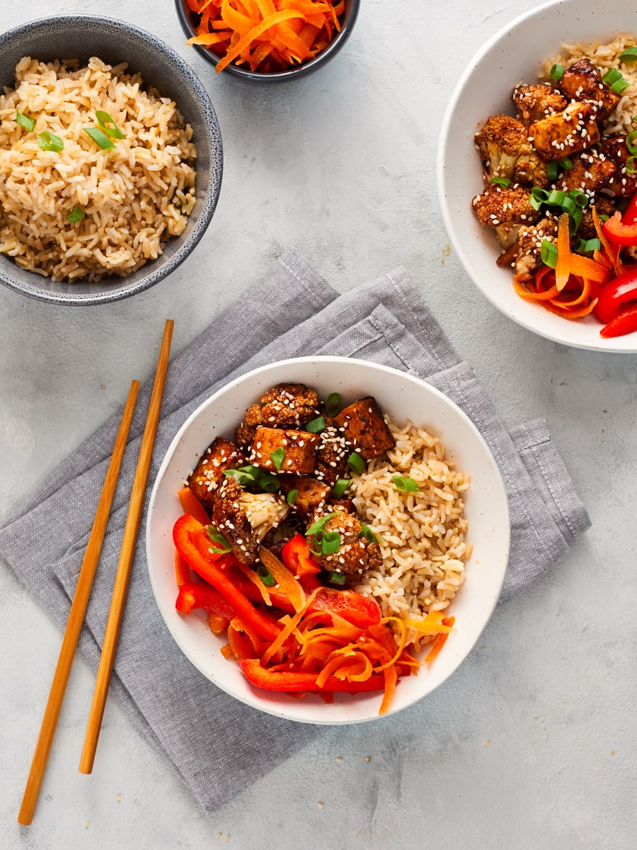 Two bowls of teriyaki tofu and cauliflower with rice and carrots