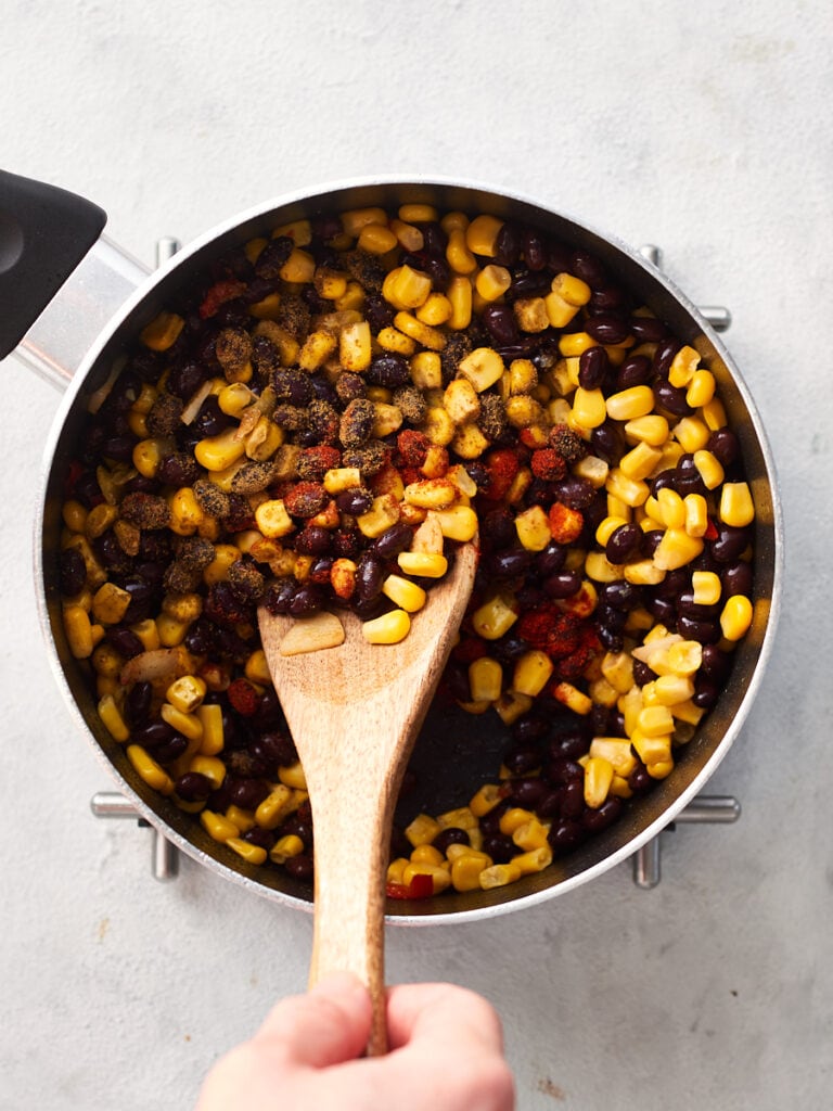 Adding spices to beans and corn
