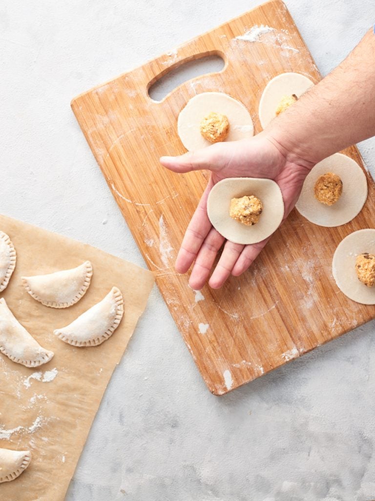 Adding a ball of filling to each dough circle