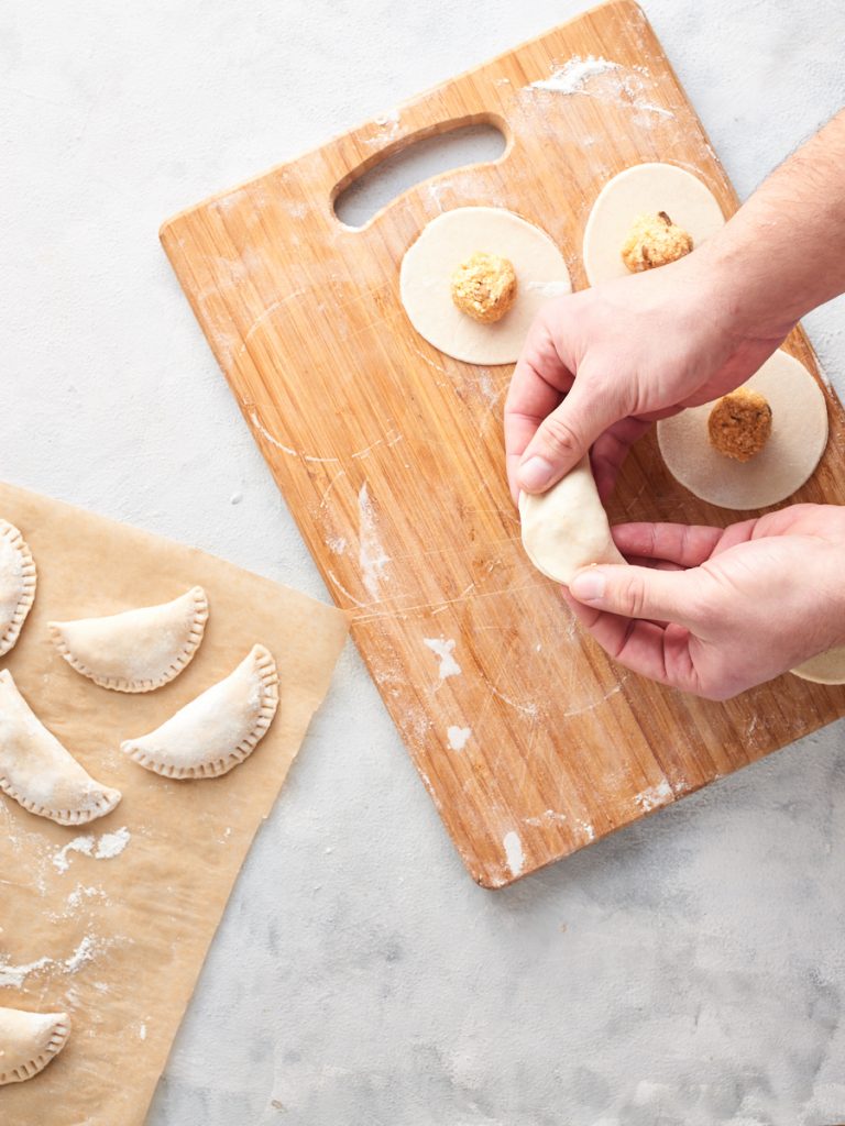 Pressing the sides of dough together to form pierogi