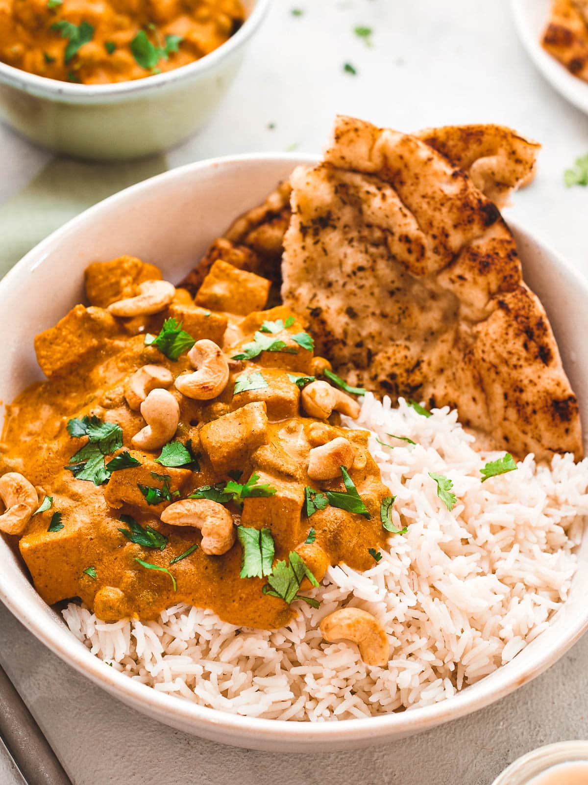 Vegan shahi korma in a bowl with rice and naan