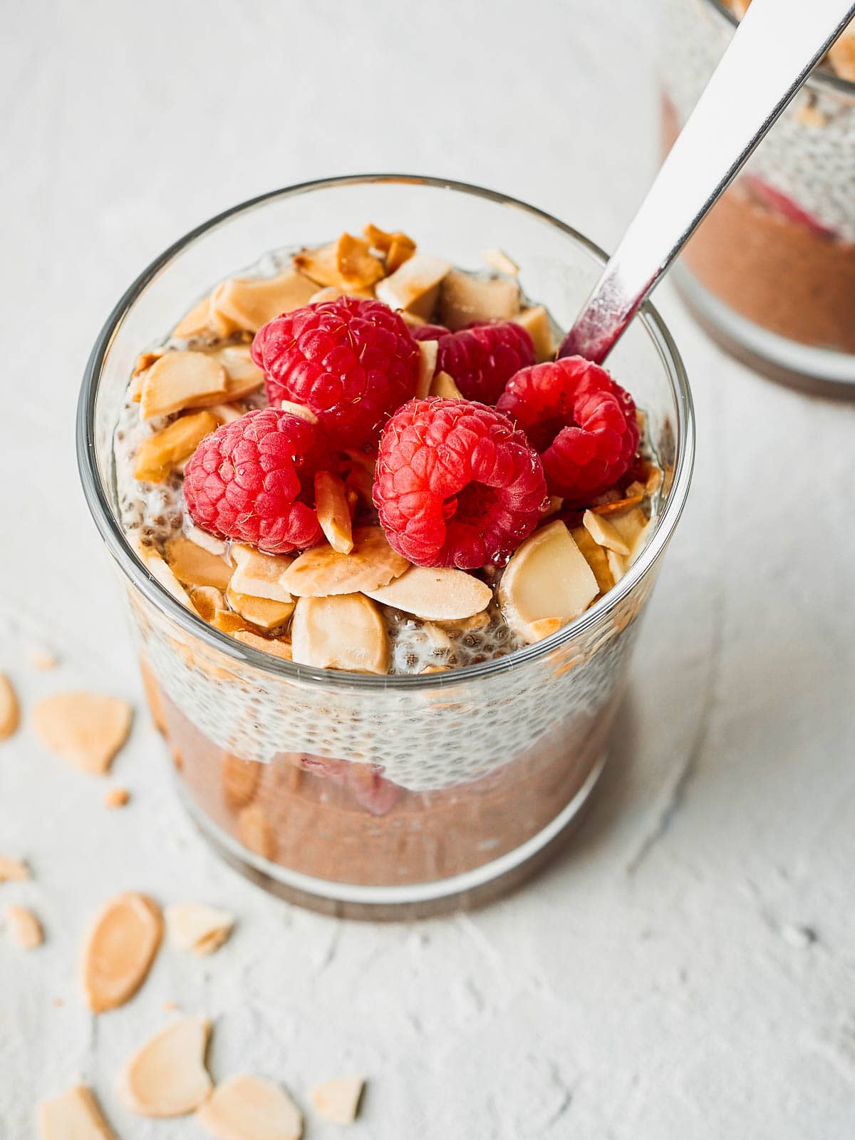 Three quarter photograph of chia pudding with raspberries and toasted almonds on top