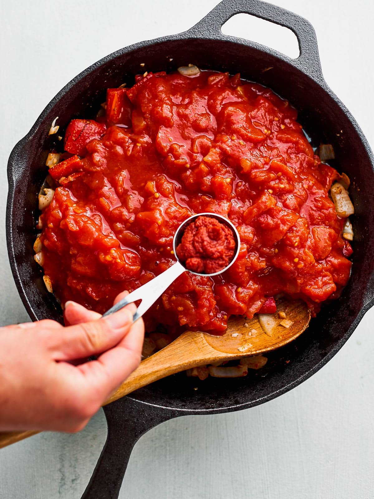 Tomato paste being added to the shakshuka sauce