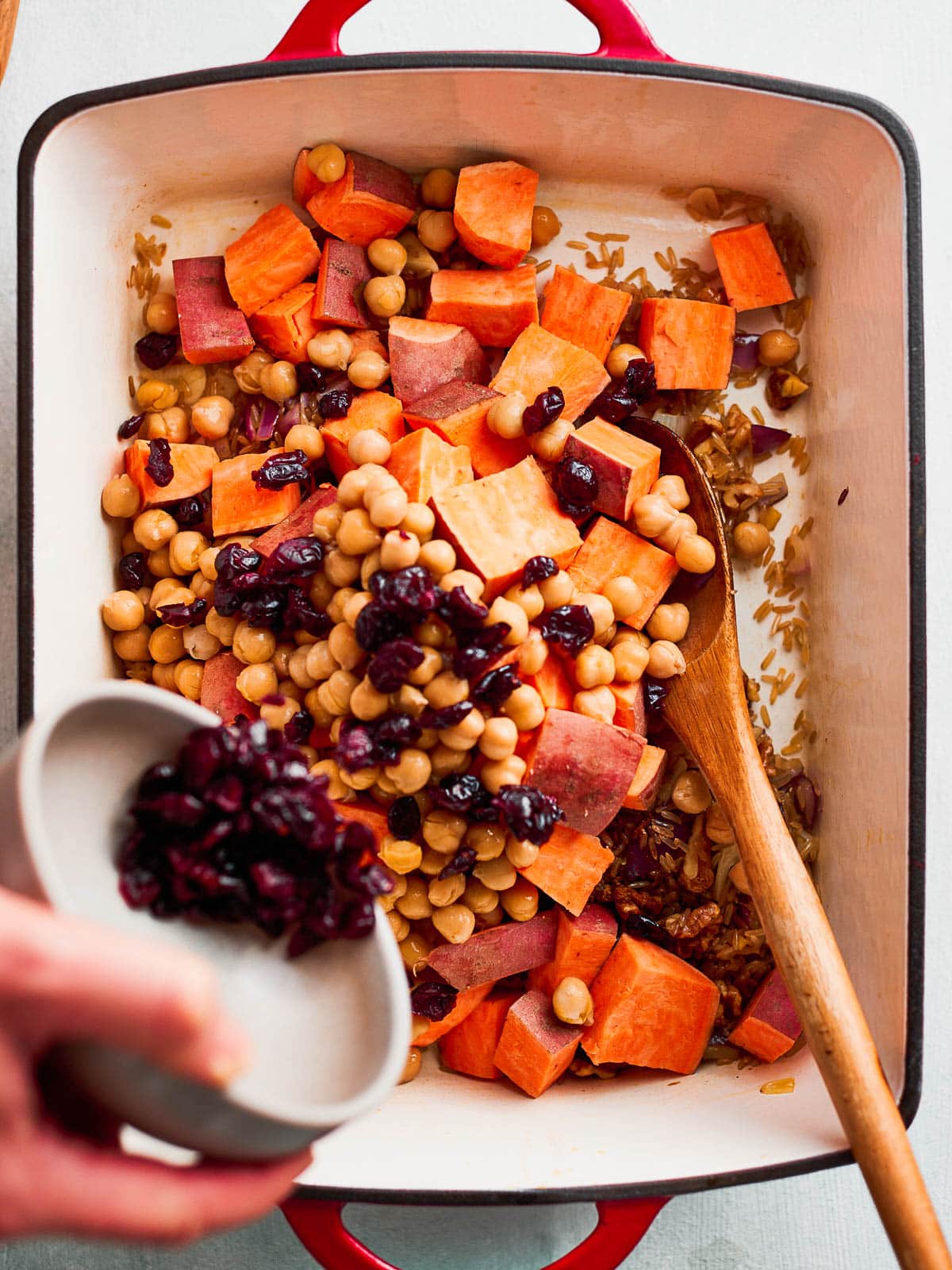 Adding the sweet potatoes, chickpeas and dried cranberries to the pan