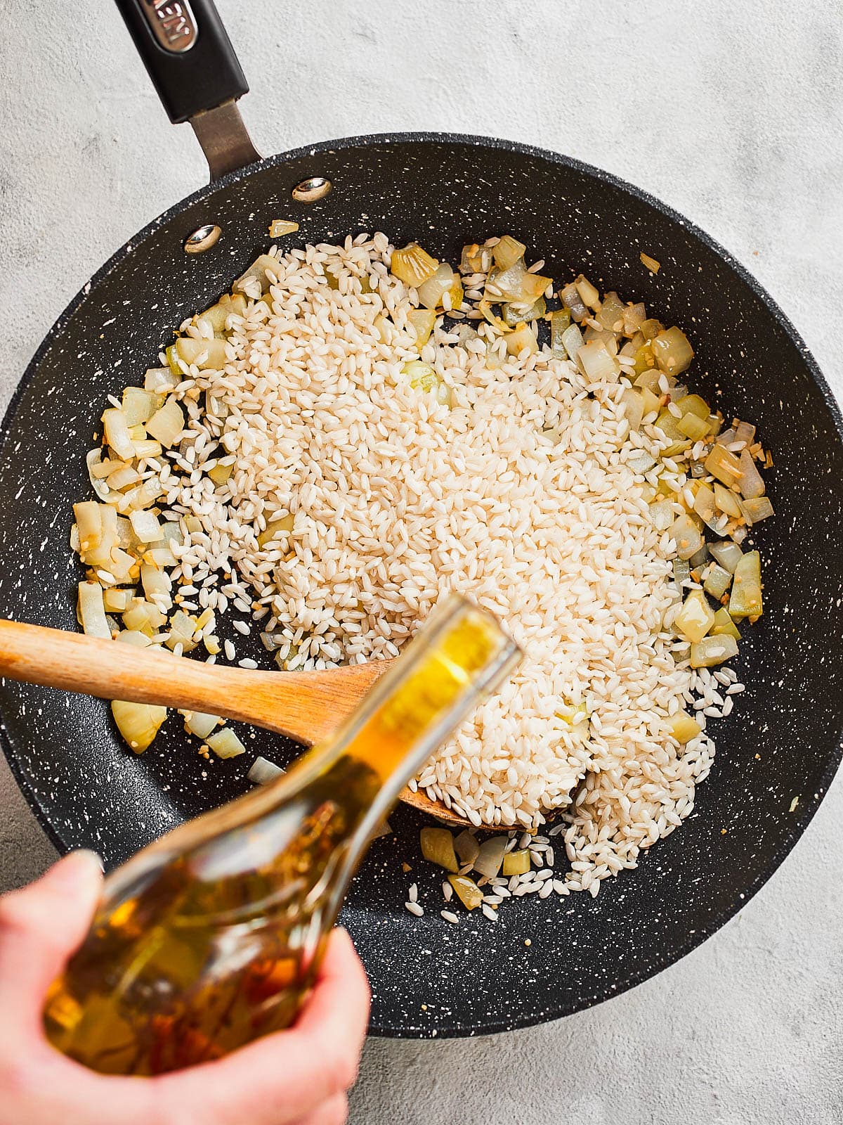 Adding olive oil into the pan to separate the grains
