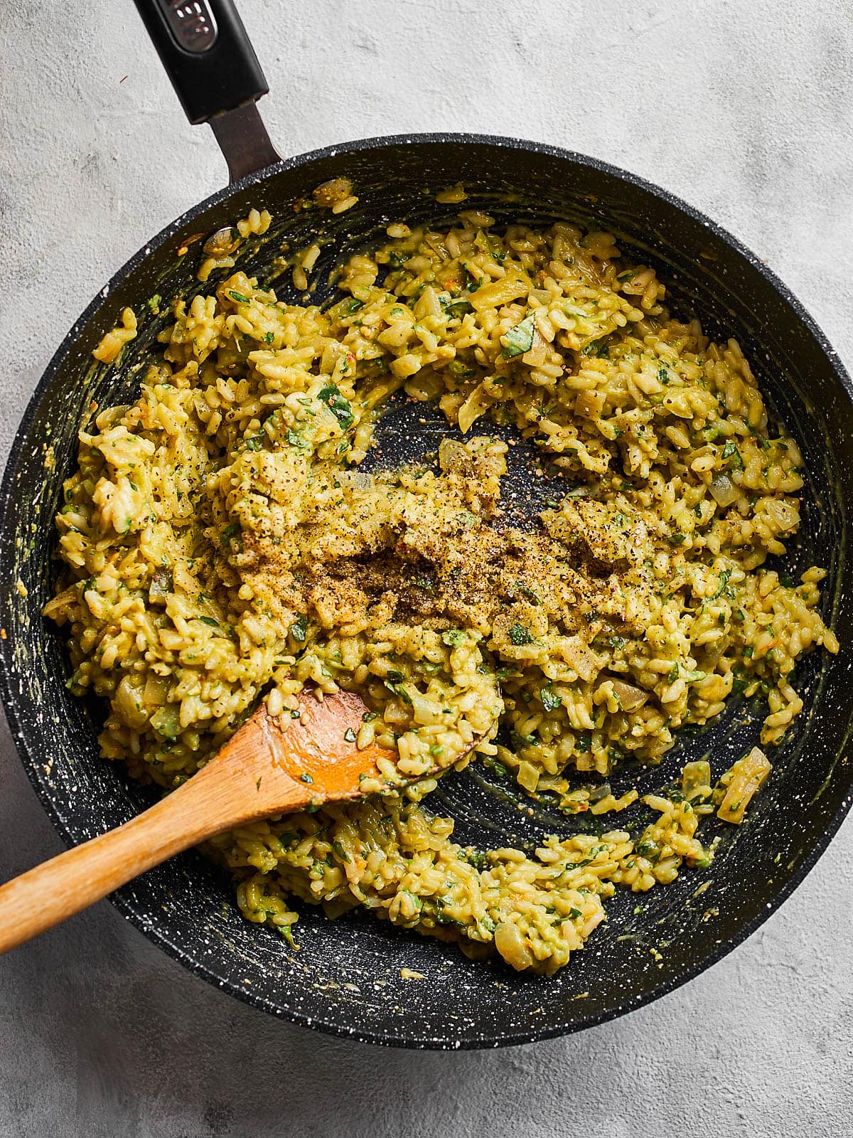 Stirring and seasoning the avocado risotto in the pan