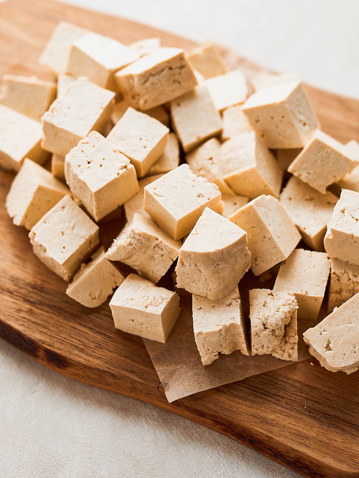 Tofu chopped into cubes on a chopping board