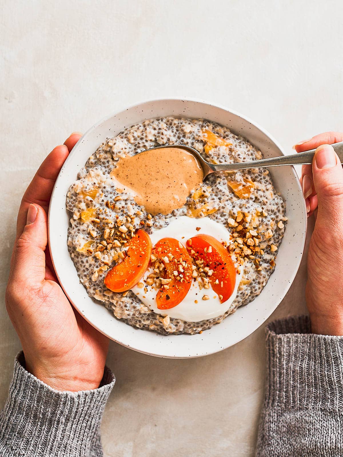 Overhead photo of a bowl of chia seed porridge with a hand holding a spoon
